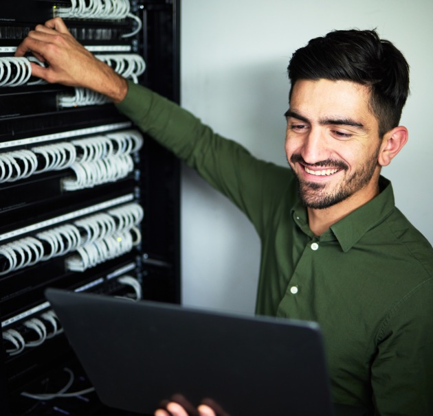 young IT professional smiling at laptop