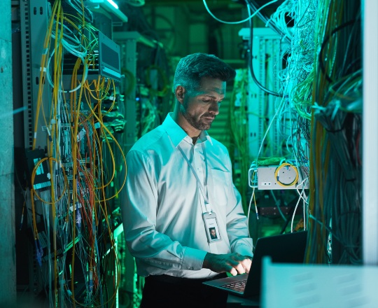 two male discussing and standing next to a laptop